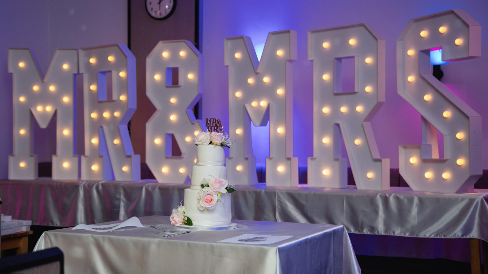 Mr & Mrs marquee letters behind a tiered wedding cake